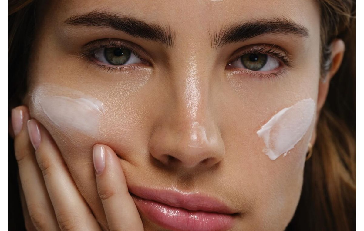 Close up of a woman with dewy skin and swatches of moisturiser on her cheeks and nose, showing a light and a richer moisturiser texture